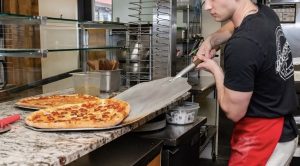 An employee placing a pizza on a countertop