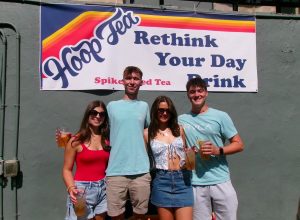 Doggie's patrons standing in front of a Hoop Tea banner